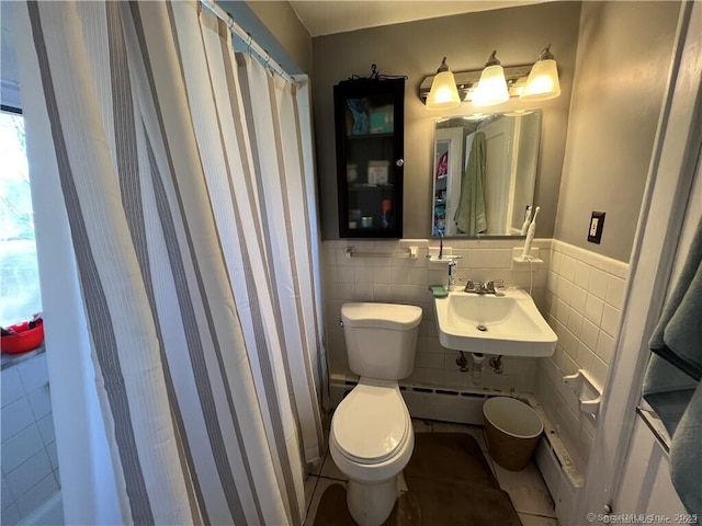 full bathroom with a baseboard heating unit, a wainscoted wall, toilet, tile walls, and a sink