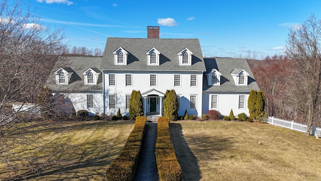 view of front of home featuring a front lawn, fence, roof with shingles, and a chimney