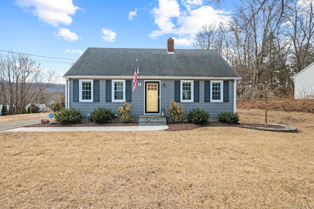 view of front facade with a chimney, a front lawn, and roof with shingles