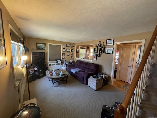 living area with stairs, radiator heating unit, plenty of natural light, and carpet floors