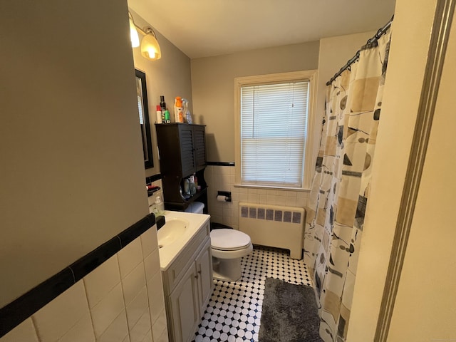 bathroom featuring a wainscoted wall, toilet, radiator heating unit, tile walls, and vanity