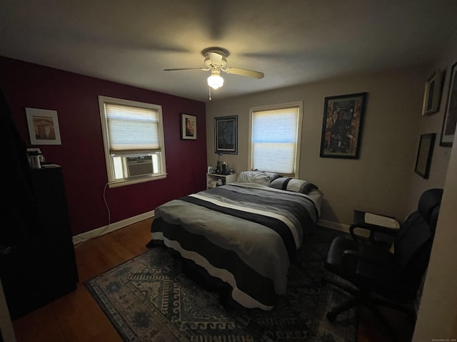 bedroom with cooling unit, baseboards, wood finished floors, and a ceiling fan