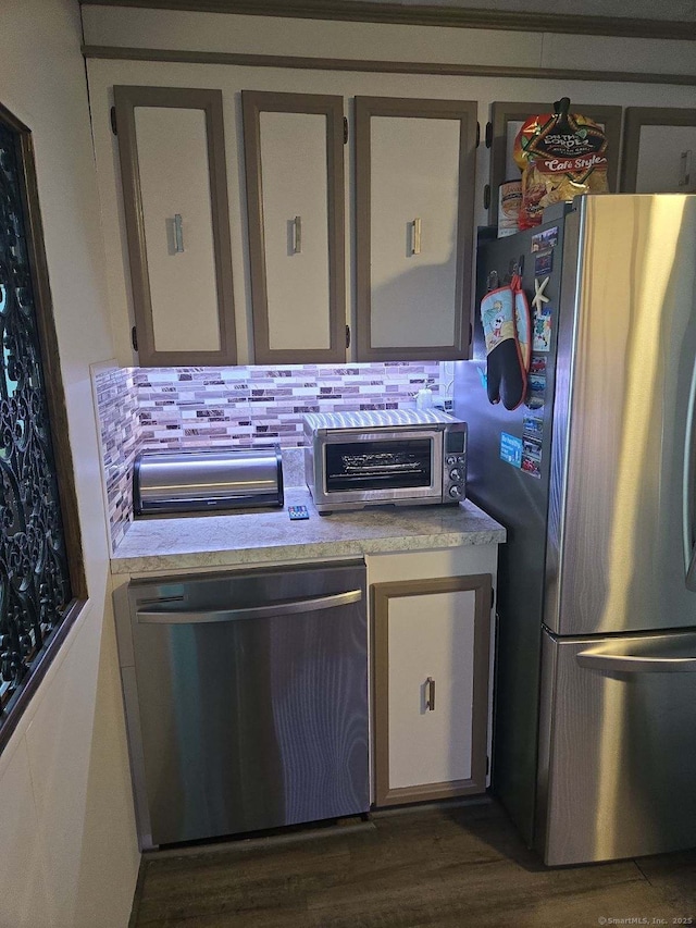 kitchen featuring a toaster, decorative backsplash, appliances with stainless steel finishes, and light countertops