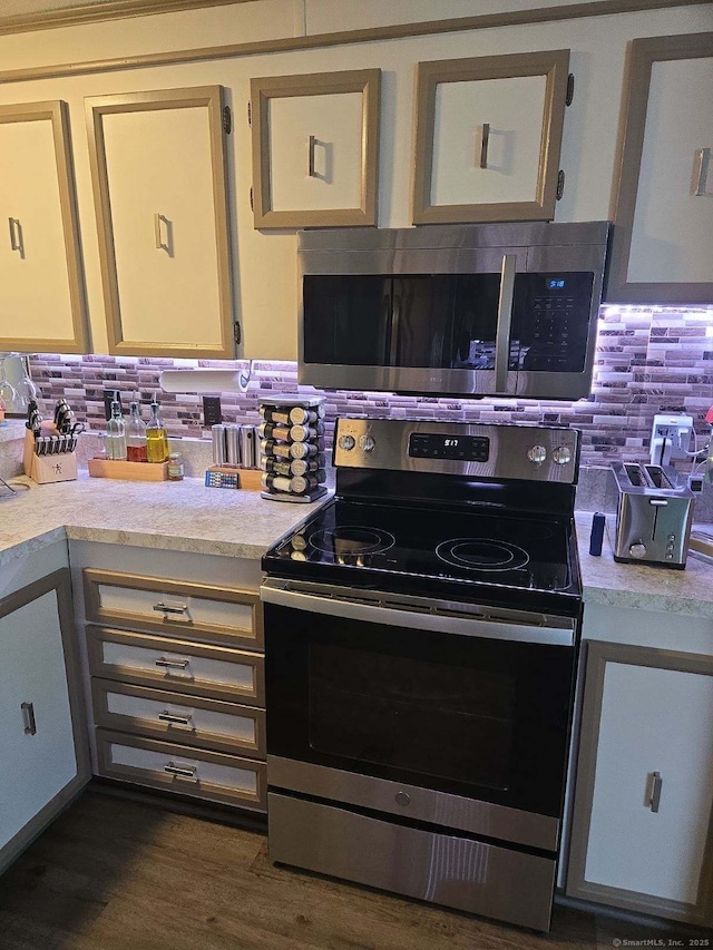 kitchen featuring dark wood-style floors, decorative backsplash, appliances with stainless steel finishes, and light countertops