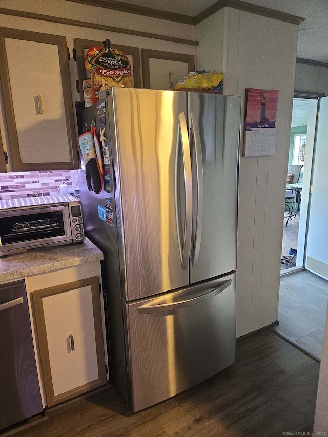 kitchen with stainless steel appliances, ornamental molding, dark wood-style flooring, and a toaster