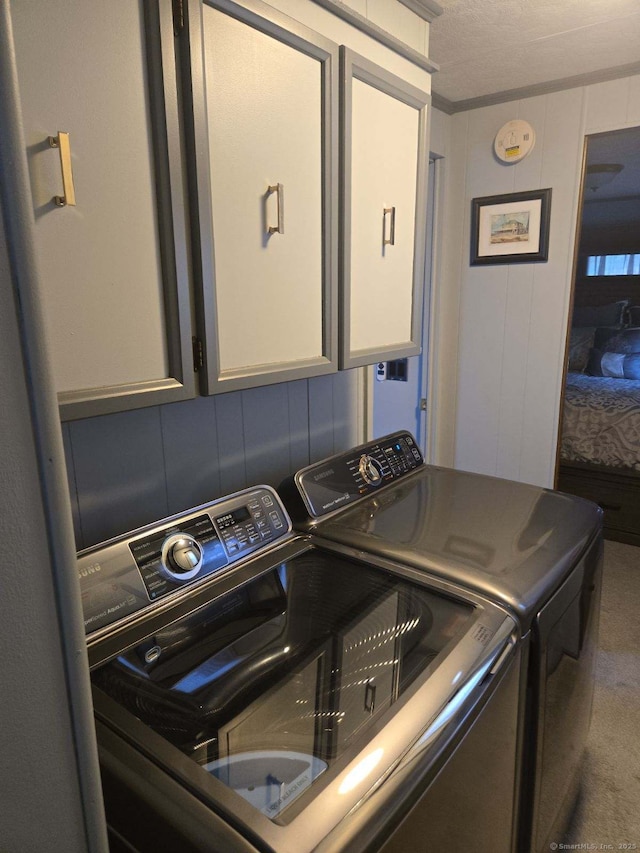 clothes washing area with cabinet space, washing machine and dryer, and carpet flooring