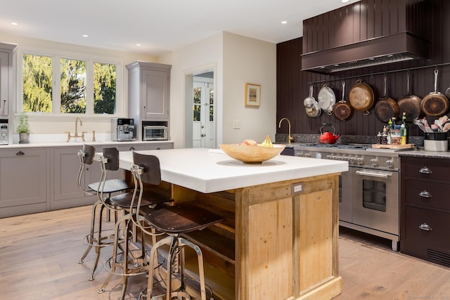 kitchen with custom exhaust hood, light wood-style flooring, a center island, and range with two ovens