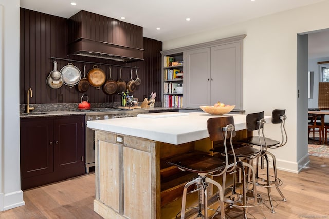 bar featuring custom range hood, a sink, gas stove, recessed lighting, and light wood finished floors