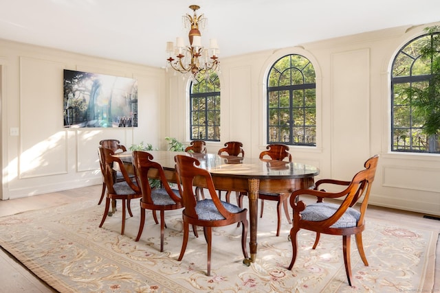 dining room with a decorative wall, light wood-style floors, and a chandelier