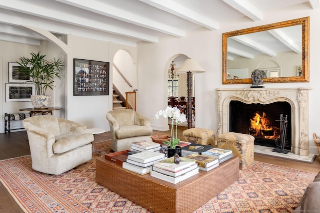 living room featuring arched walkways, stairs, a high end fireplace, and wood finished floors