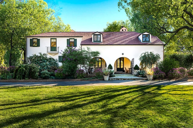 mediterranean / spanish house featuring a front lawn and stucco siding