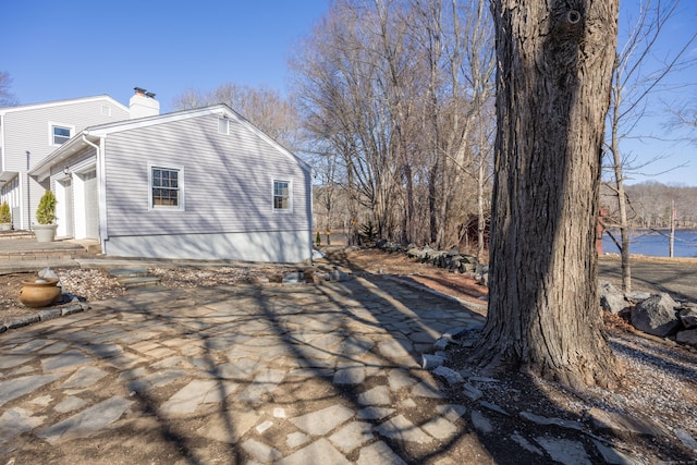 view of side of home featuring a garage and a chimney