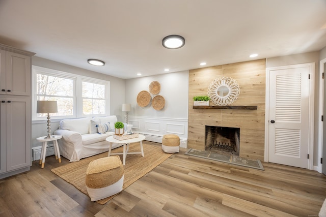 living room featuring recessed lighting, light wood-style floors, a tiled fireplace, and baseboard heating