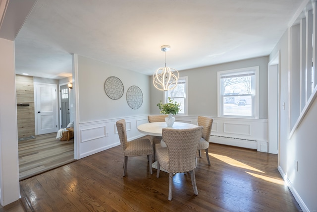 dining area with a wainscoted wall, a baseboard heating unit, dark wood-style flooring, and a notable chandelier