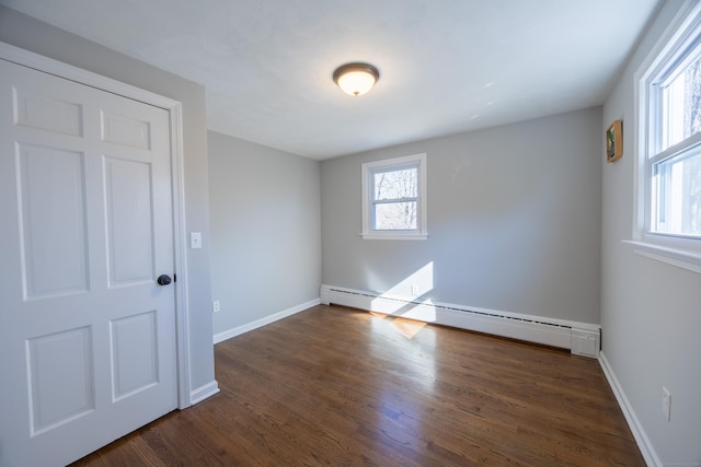 unfurnished room with baseboards, baseboard heating, and dark wood-style flooring