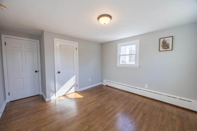 unfurnished bedroom with wood finished floors, baseboards, a closet, and a baseboard radiator