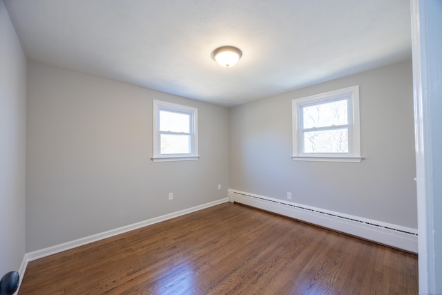 spare room with baseboard heating, baseboards, and wood finished floors