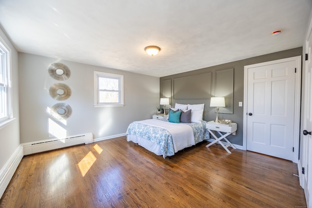 bedroom with a baseboard radiator, baseboards, and wood finished floors