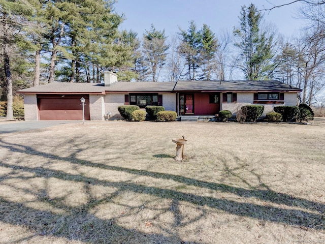 single story home with brick siding, driveway, a chimney, and a garage