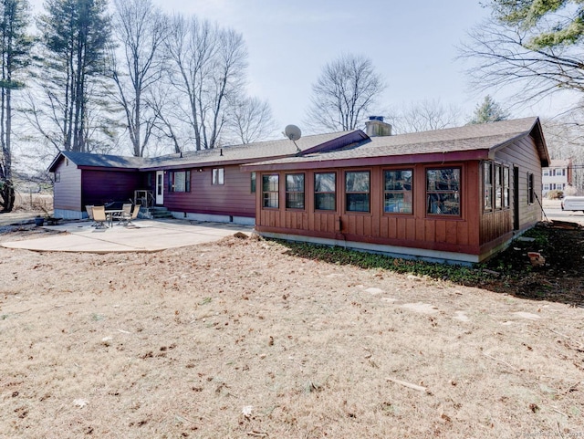 rear view of property with entry steps, a patio area, a shingled roof, and a chimney