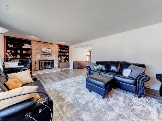 living area featuring built in features, a large fireplace, and wood finished floors