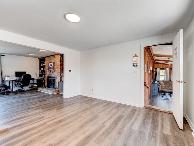 living area with a fireplace, baseboards, and wood finished floors