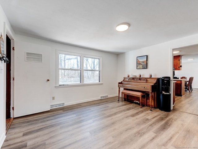 living area with light wood-style floors, visible vents, and baseboards