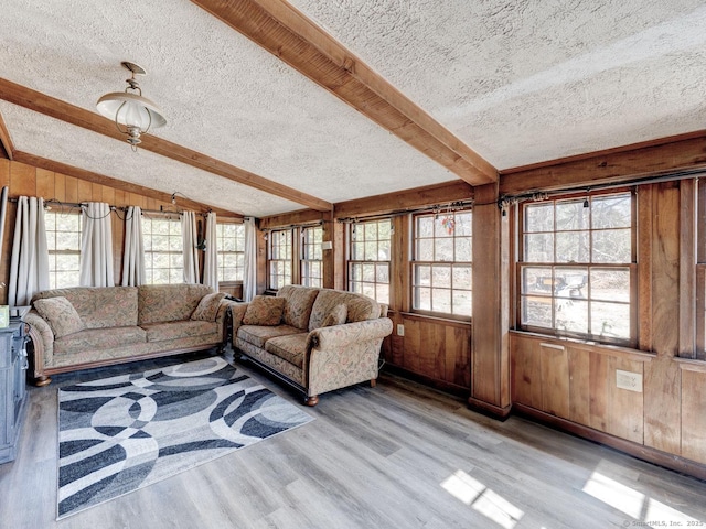 living area with vaulted ceiling with beams, wood finished floors, wood walls, and a textured ceiling