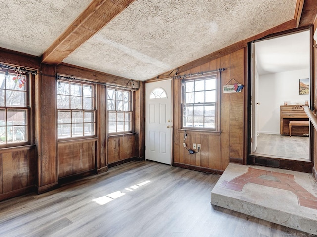 foyer with lofted ceiling, a textured ceiling, wood finished floors, wood walls, and baseboards