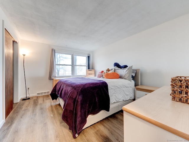 bedroom with light wood-type flooring and a baseboard radiator