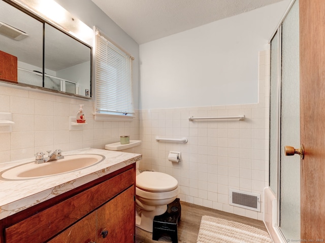 full bath with vanity, wood finished floors, a shower with shower door, visible vents, and toilet