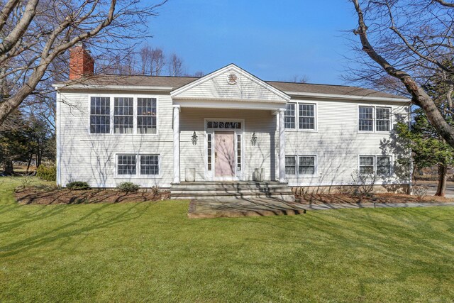 raised ranch with a chimney and a front lawn