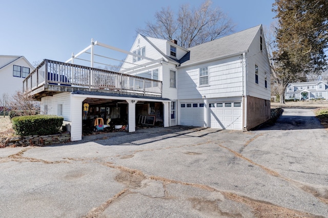 exterior space with a garage, a chimney, and aphalt driveway