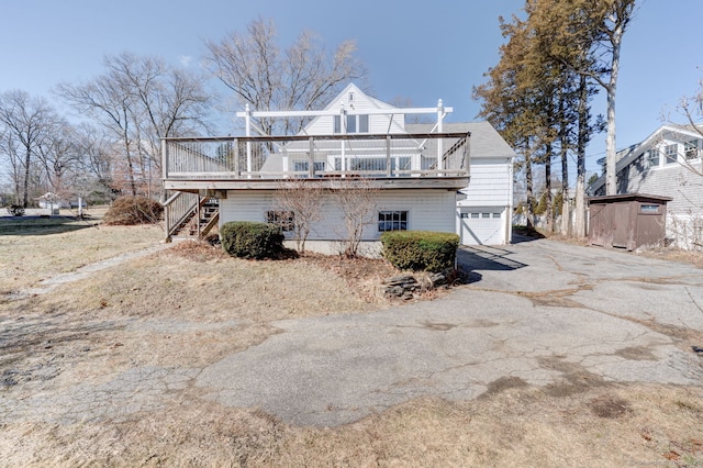 exterior space with aphalt driveway, an attached garage, and stairs