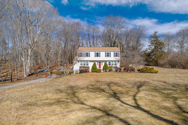 colonial house featuring a front yard and a chimney