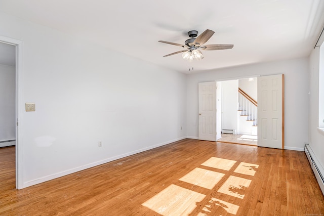 spare room with light wood finished floors, a baseboard heating unit, and baseboards