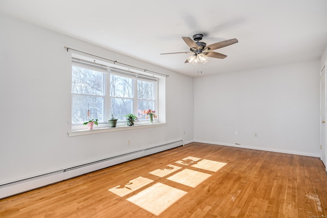 empty room featuring wood finished floors, baseboards, baseboard heating, and ceiling fan