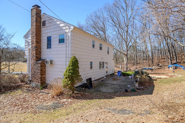 view of home's exterior with central air condition unit, a chimney, and a patio area