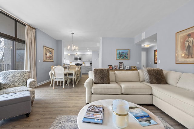 living area featuring baseboards, a notable chandelier, and wood finished floors