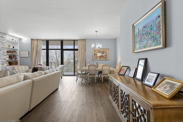 living area with a chandelier, built in features, expansive windows, and wood-type flooring