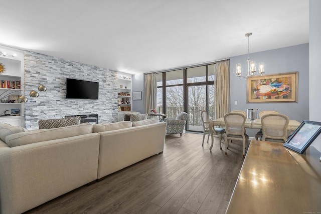 living area with built in features, expansive windows, a notable chandelier, and wood finished floors