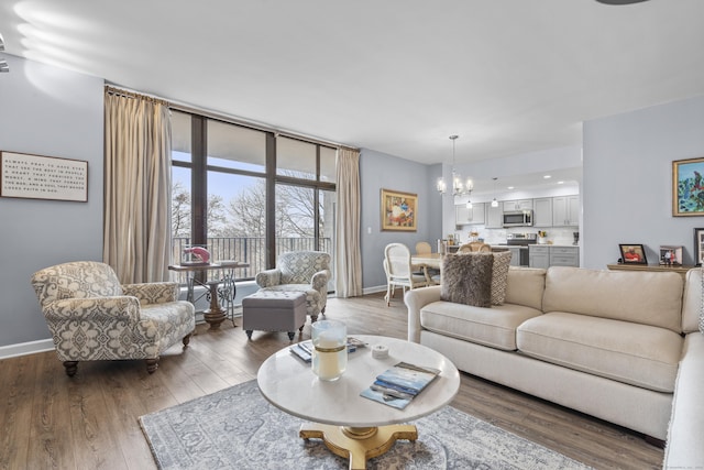 living room featuring a chandelier, floor to ceiling windows, baseboards, and wood finished floors