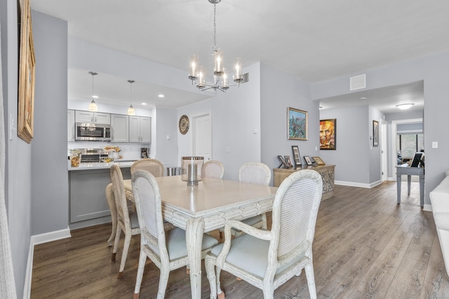 dining area with visible vents, baseboards, an inviting chandelier, and light wood finished floors