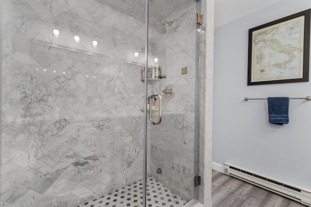 full bathroom featuring a marble finish shower, a baseboard heating unit, and wood finished floors