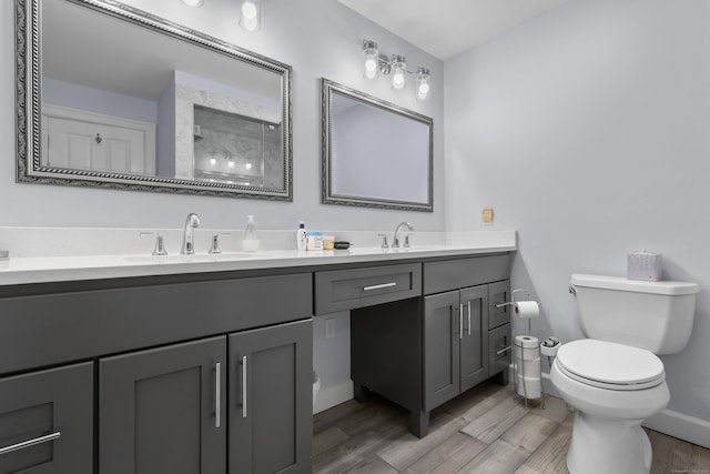 bathroom featuring double vanity, toilet, wood finished floors, and a sink