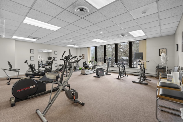 exercise room featuring baseboards, visible vents, a drop ceiling, and expansive windows