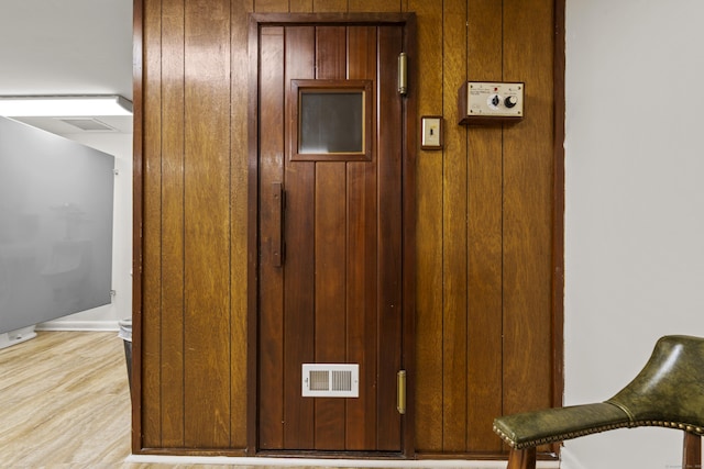 details with wood finished floors, visible vents, and wood walls