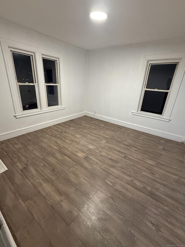 unfurnished room with baseboards and dark wood-style flooring