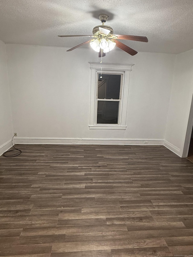 unfurnished room with dark wood finished floors, ceiling fan, a textured ceiling, and baseboards