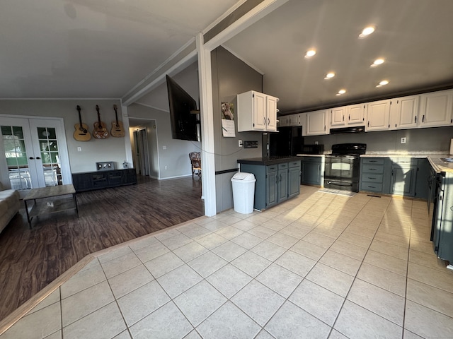 kitchen with light tile patterned floors, black appliances, white cabinets, vaulted ceiling, and under cabinet range hood